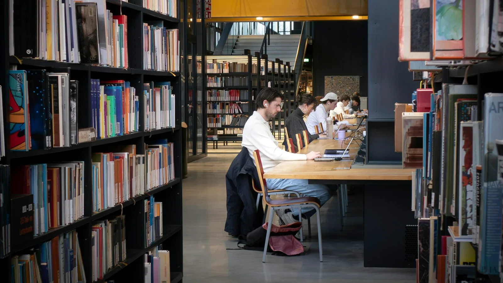 Students studying at long tables in a modern library